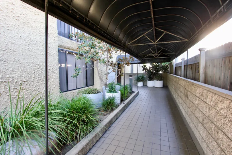 A sunny day in the area of Cresthill Plaza, walkway, brick, covered, potted plants