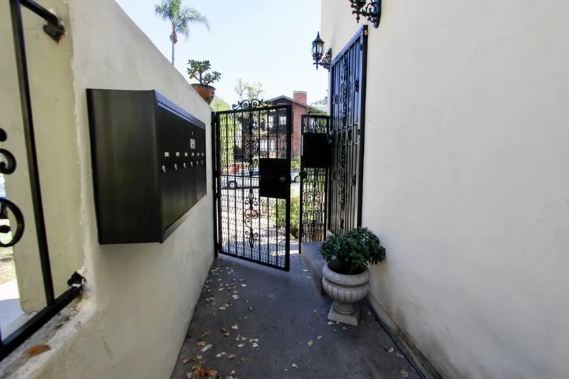 Narrow walkway with community mailboxes leading to a gated entrance to the Las Casas De Juan community in Mission Hills, CA