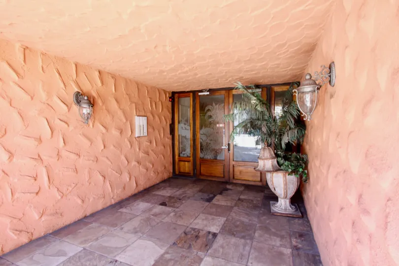 the tiled entrance to a home with a decorataive planter and greenery next to the wooden and etched glass door in the Terrace Village community in Mission Hills California