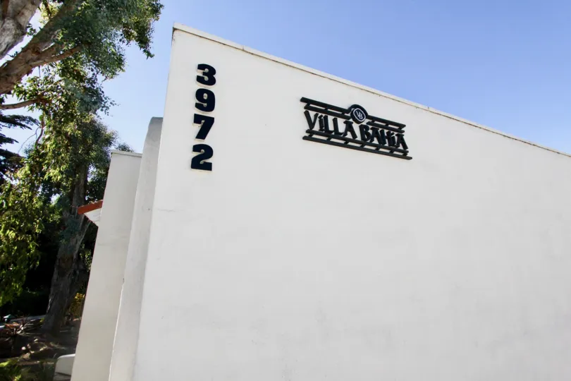 A sunny day on a tree lines street in front of Villa Bahia, with Building number showing, in Mission Hills, CA
