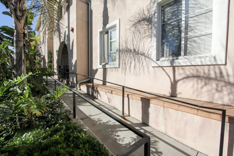 Gray paved sidewalk lined with plants at villa Portofino on Front in Mission HIlls CA