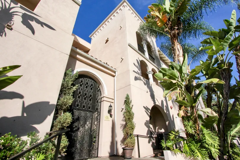 A luxurious building with very tall palm trees at the front during a sunny day in Villa Portofino on Front, Mission Hills, CA
