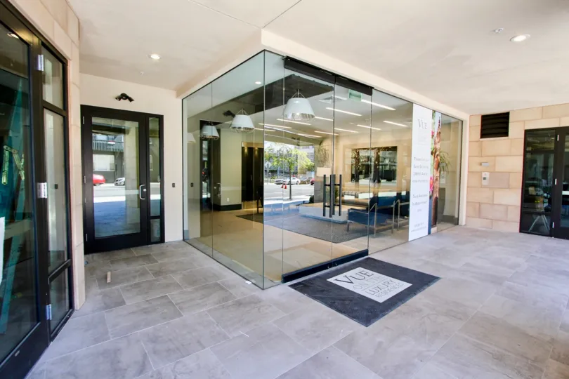A modern community room enclosed in glass in the lobby of the Vue on 5th building.