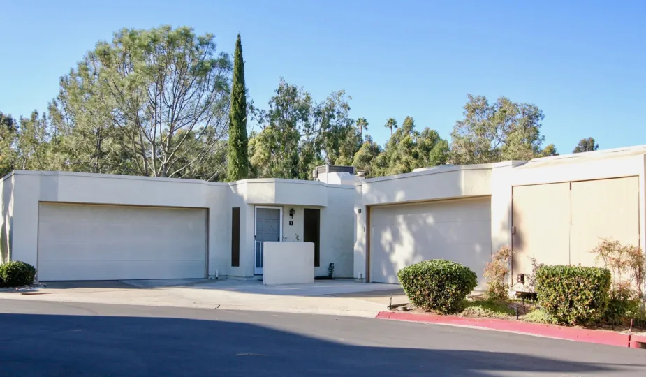 A unique and modern house. Flat, white, and with multiple garage doors.