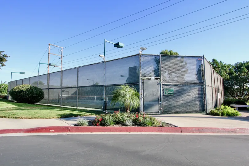 Fenced-in tennis courts by a road surrounded by grass in Cerro De Alcala, Mission Valley, California