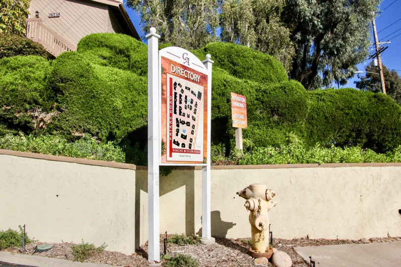 A directory and parking sign for Friars Mission community, next to a fire hydrant