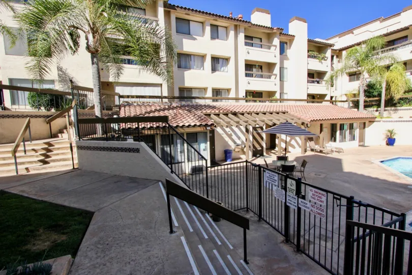 A sunny day poolside in the area of Mission Greens, palm tree, balcony, condos, stairs