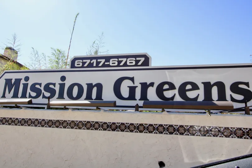 A sunny day in the area of Mission Greens, main sign, trees
