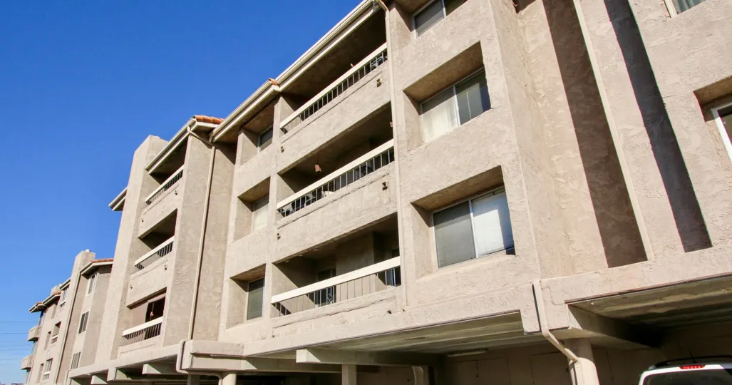 A white Suv sits in the shade under an residential building at the Mission Ridge condos.