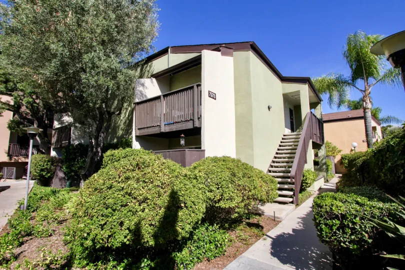 A view of the exterior stairs and balcony in Park Villas North including the sidewalk and professional landscaping.