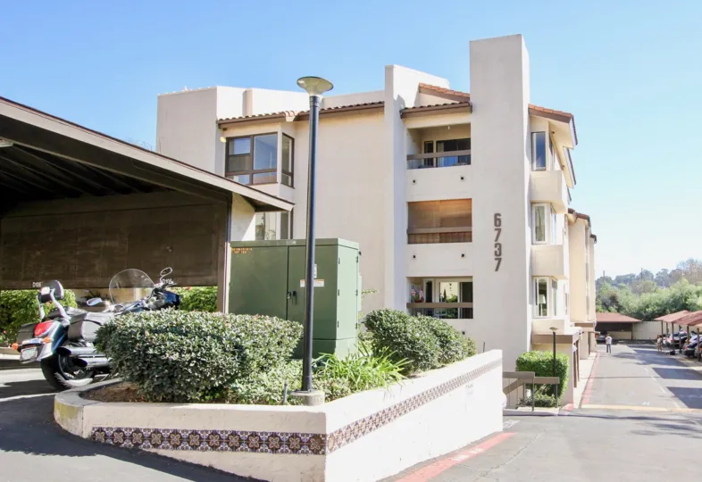 The exterior of 6737 River Scene apartments showing the street adjacent and the car port