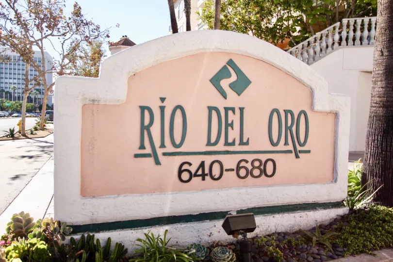 A sign that says Rio Del Oro behind a flowerbed at Rivery Scene in Mission Valley California