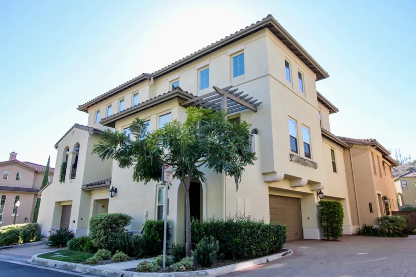 Three story apartment building with garage and bushes.