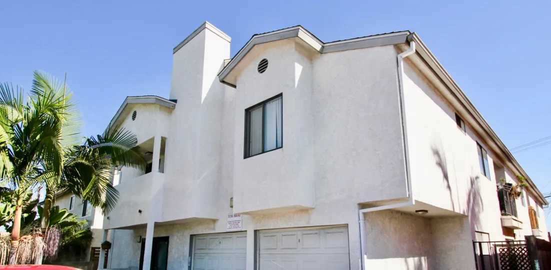 A sunny day in the area of A2I Condominiums, palm trees, garages, condos, balcony