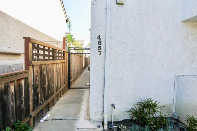 A closed black gate next to a wooden fence alongside the A2I Condominiums in Normal Heights, California.