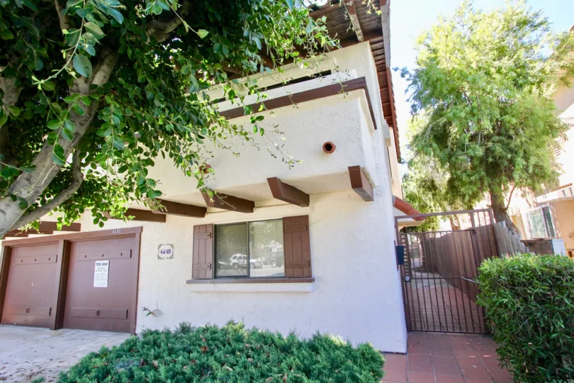Garages and gated walkways with shade trees at the Aspen Villas in Normal Heights, California