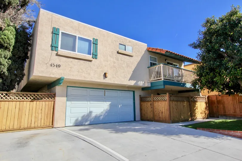 Front of a building in Bancroft Normal Heights in Normal Heights, CA, showing a garage, balcony, and fence