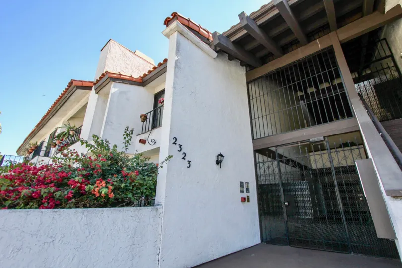 A sunny day in the area of Casa Monterey, outside, gated entrance, flowers, stairs, balcony