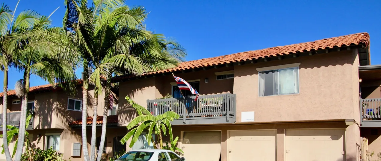 A peach colored condo with tiled roofs surrounded by palm trees in Normal Heights