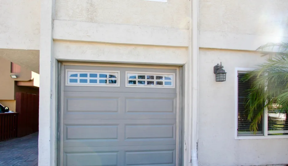 A gray garage door with small windows next to a porch light at Element on Iowa in Normal Heights CA