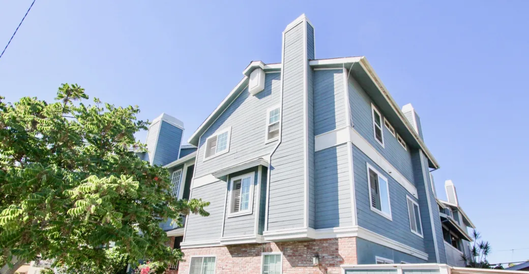 A three story blue condominium with a red brick wall at Madision ave in Normal Heights CA
