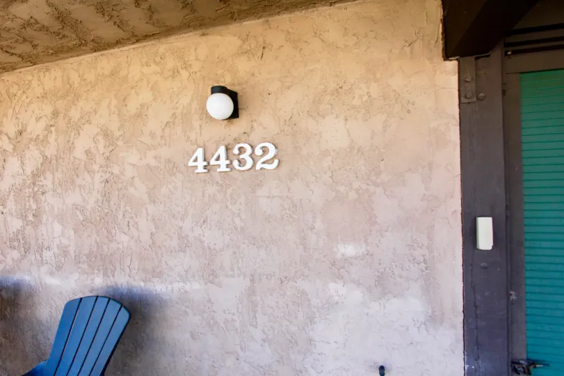 The front door, a lawn chair, address plate, and lighting of a home in Magnolia Manor, Normal Heights, CA.