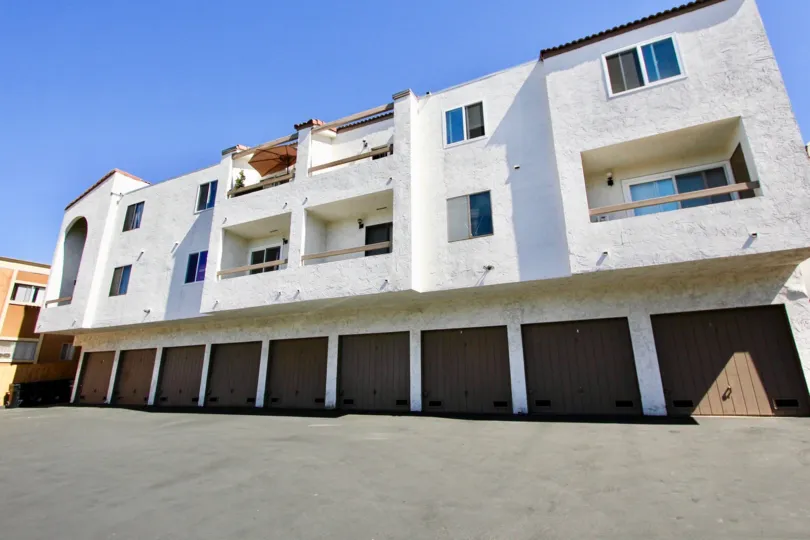 A sunny day a wight color big building car parking area in the Mission Villas near the road side.