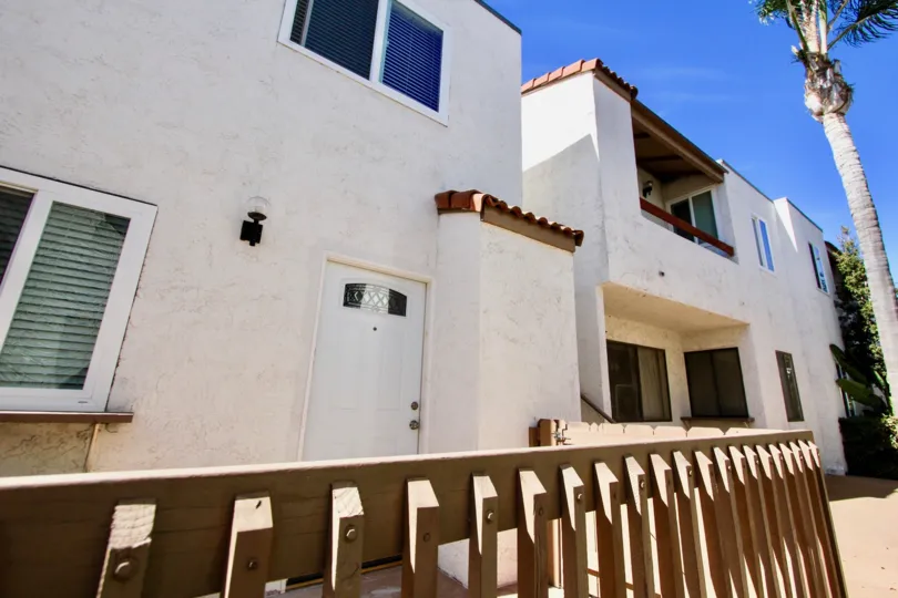 The exterior of a unit at the white stucco Mission Villas condo complex under a blue sky.