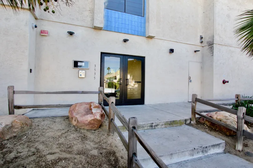 A sunny day in the area of Monroe Manor, outside, rock, stairs, glass door, buzzer, palm tree