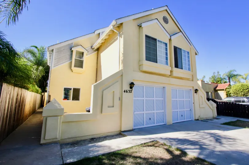 A sunny day in the area of Norman House II, outside, driveway, garage, window, wooden fence