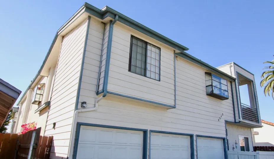 A clear sky view seen from the backyard with three garage for cars.