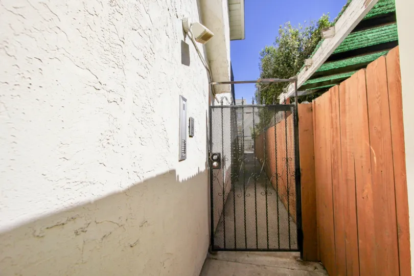 A sunny day in the area of Oaktree Villas, gated entrance, wooden fence, sidewalk, roof, tree