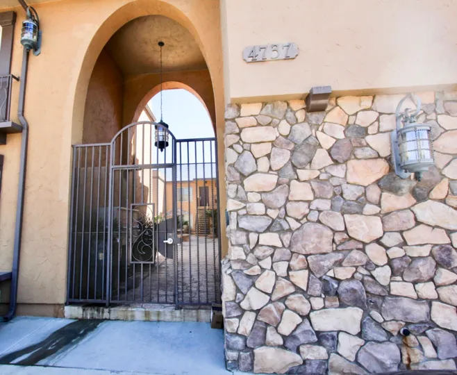 Black iron gate next to address and stone wall at Normal Heights in On 34th CA