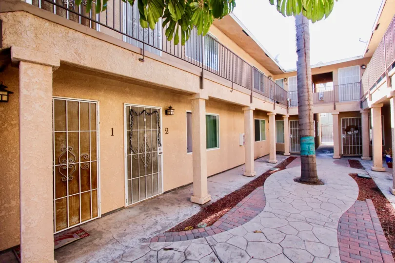 Courtyard with mature palm trees and cobblestone pathway lined with red brick at Palm Terrace
