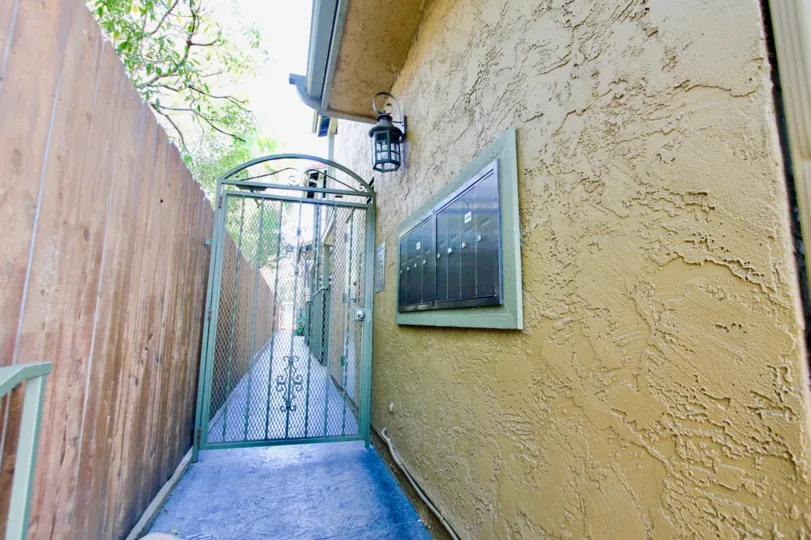 Gated access to Park Place apartment with a tall fence and yellow building