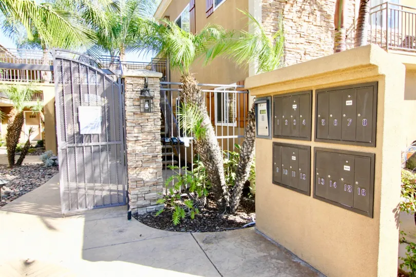 A sunny day in the area of Stone Manor, mailboxes, gate, palm trees, stones, sidewalk, condos