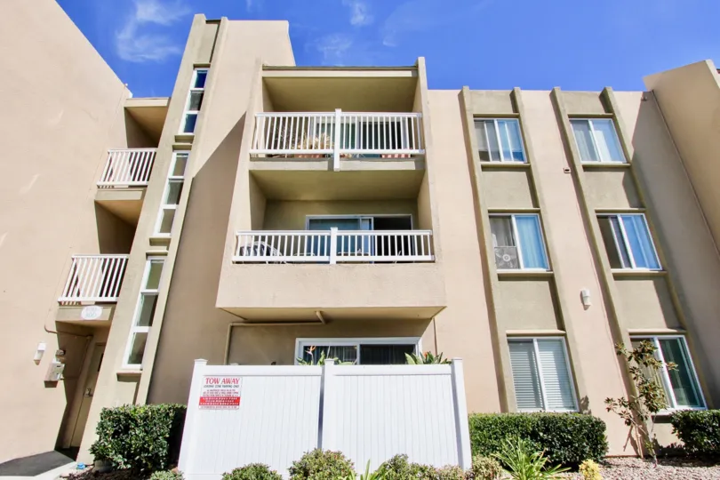 A sunny day in the area of Suncrest Villas, outside, balconies, fence, bushes, high rise