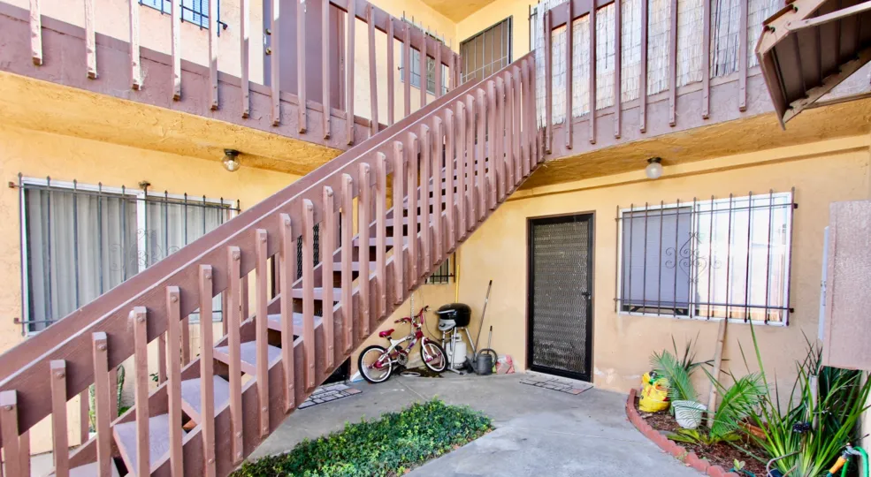 A staircase leads up a floor in an apartment block in Normal Heights with a bicycle leaning against a wall.