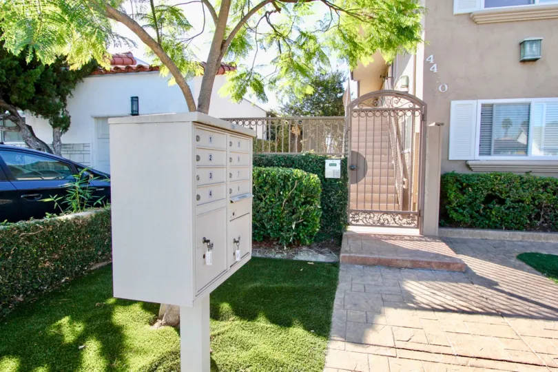 Community mailboxes and gated secure entryway with manicured lawns and shrubs at Utah West Villas