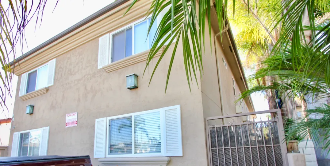 The corner view of a building in Utah West Villas, with a tree outside.
