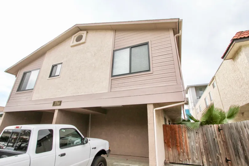 Residential building with white truck parked outside and wooden fence