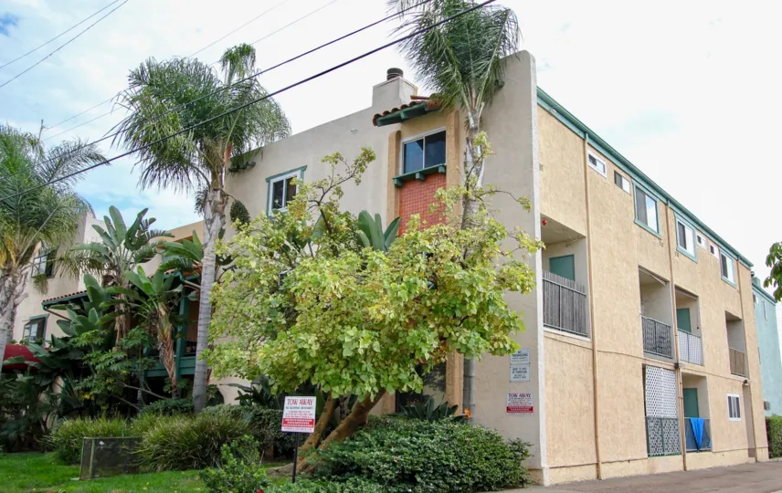 Bramson Place community in North Park, California; three story stucco building with palm trees outside.