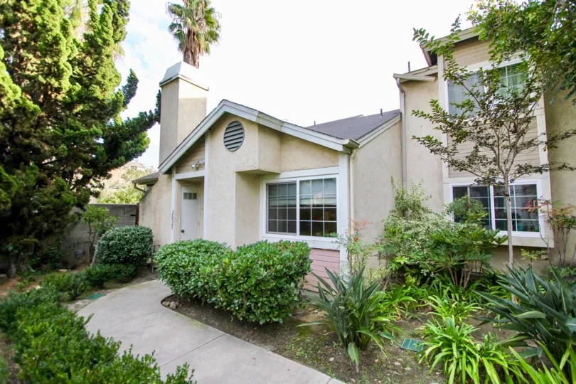 Bushes and plants are covered to the pathway of the house in the California Village