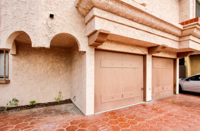 Large pink house with 2 car garage and silver vehicle.