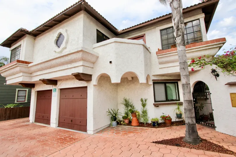 A light colored unit with a palm tree out front located within Casa Frontera II of North Park, California