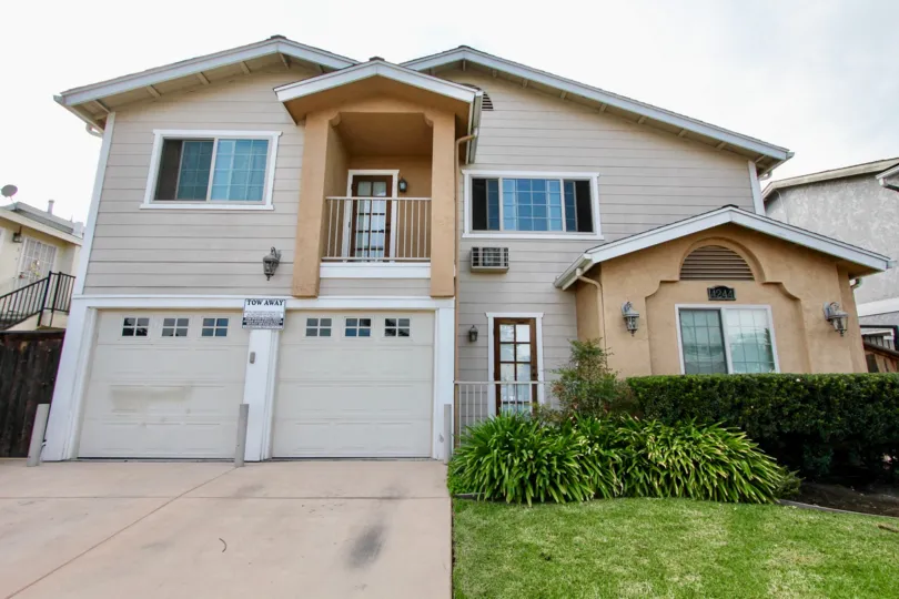 Two story building with gray garages with bushes inside Cherokee Villas at North Park CA