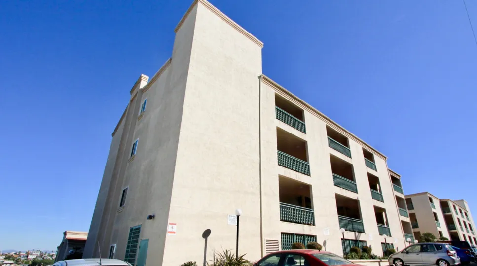A large, cream colored 4 story building with balconies on each of the levels in Coral Ridge in North Park, California.