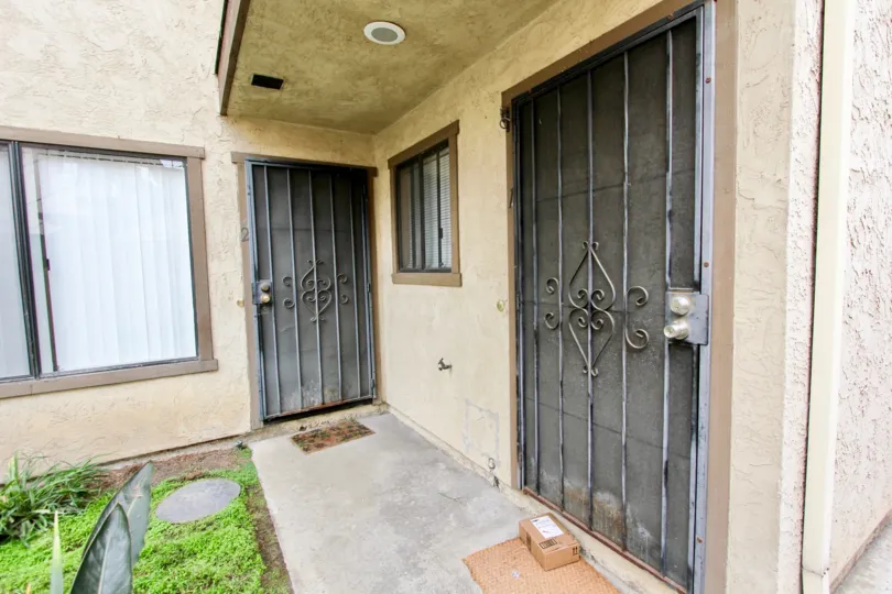 two old, front doors at apartments at Florida Park, with a package at the foot of one door