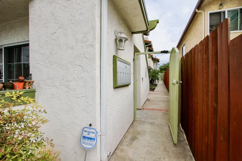 A sunny day in the area of Grim Townhomes, doorway, walkway, wooden fence, mailbox