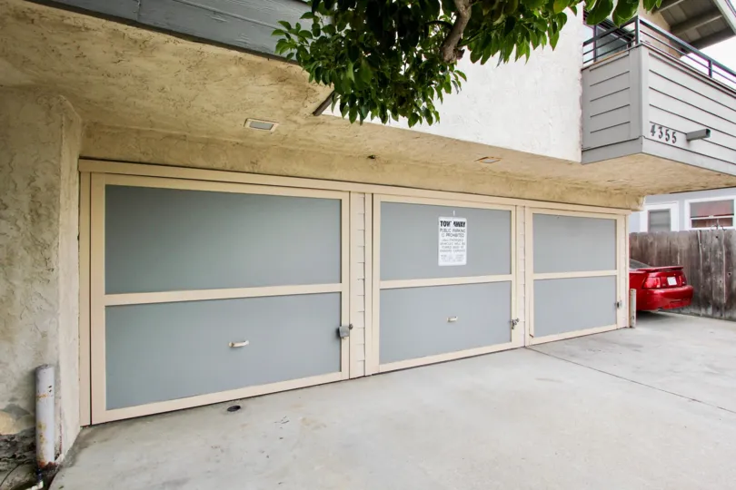 Closed garage doors and parked red car in Kentwood Condos in the city of North Park, CA